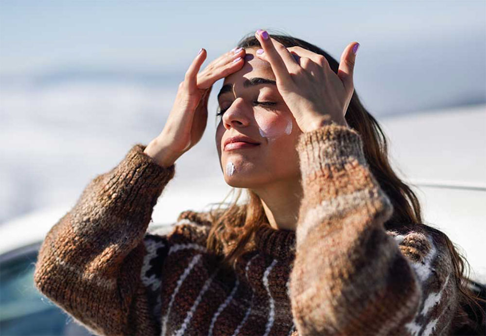Woman applying sunscreen to forehead
